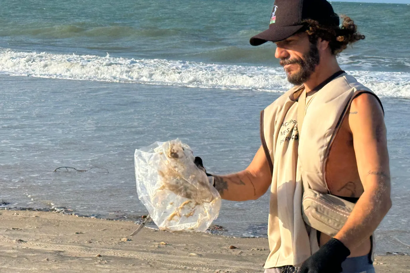 Colaborador da Carmel recolhendo resíduos na faixa de praia